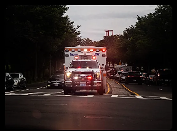 An ambulance responding with emergency lights on at dusk